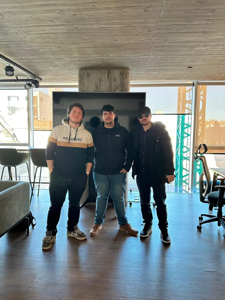 Tres personas posando juntas en un espacio de trabajo luminoso