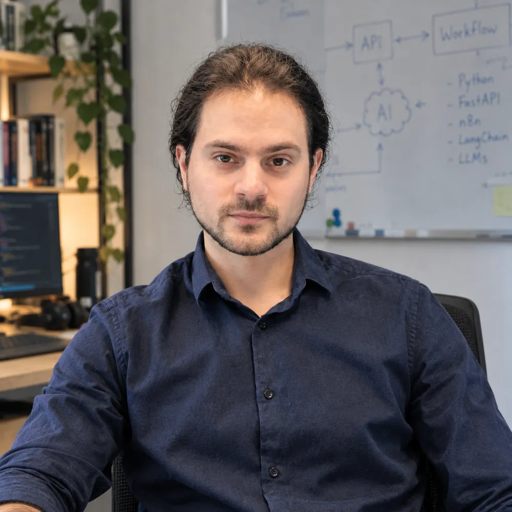 Juan Sebastián Cabrera en su espacio de trabajo, con un pizarrón de arquitectura de APIs, workflows e IA detrás